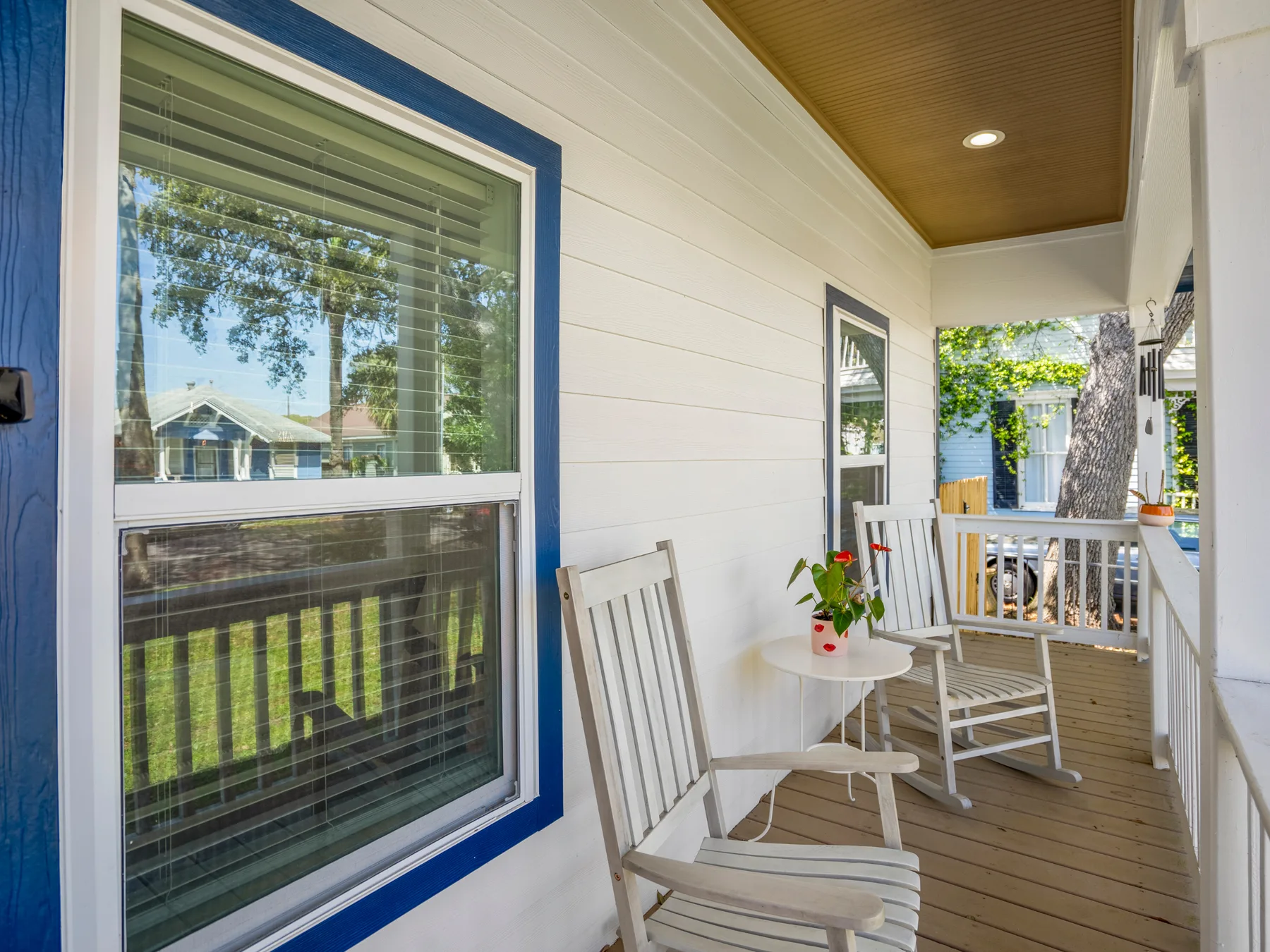 A covered porch with white seating and a small round table.