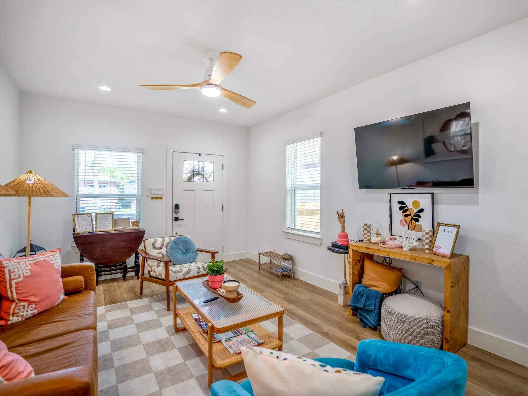 A bright living room with seating, a coffee table, and a wall-mounted television.