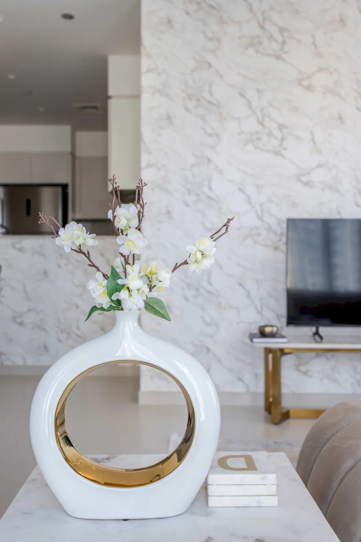 Un jarrón blanco con flores está sobre una mesa de centro en una sala de estar.