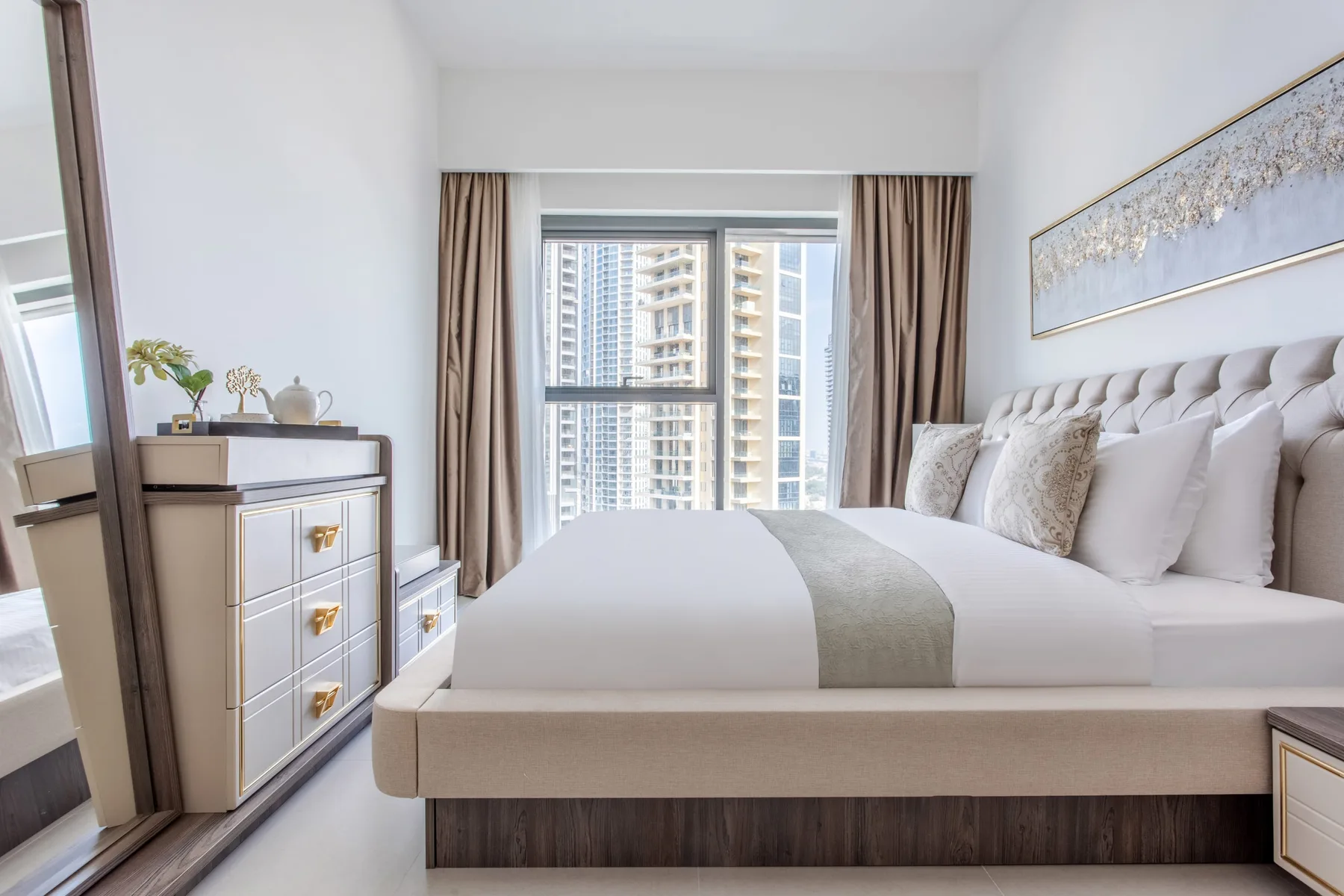 Un dormitorio con una cama bien tendida y una ventana grande con edificios a la vista.