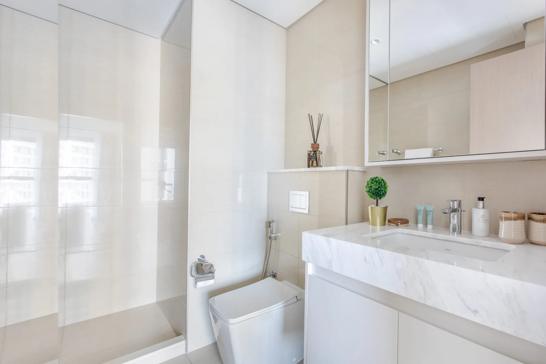 Un baño luminoso con ducha de vidrio, inodoro y un amplio tocador.
