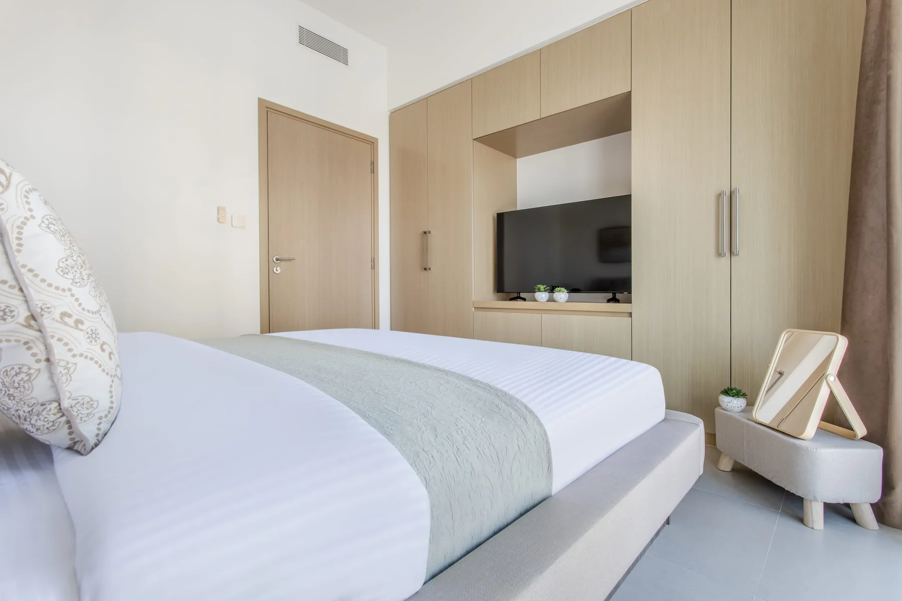 Un dormitorio con una cama bien tendida y un televisor integrado en los armarios.