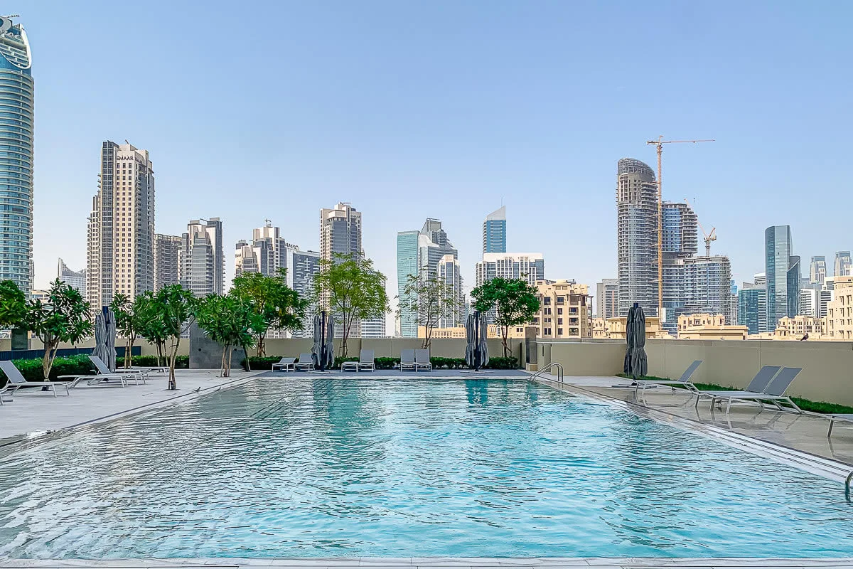 Una piscina en la azotea ofrece vistas del horizonte urbano, con asientos junto a la piscina.