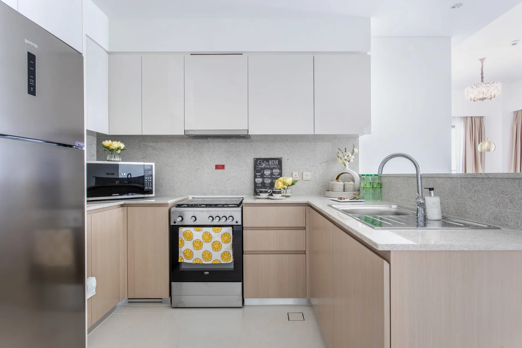 Una cocina moderna y luminosa con gabinetes claros, estufa y fregadero.