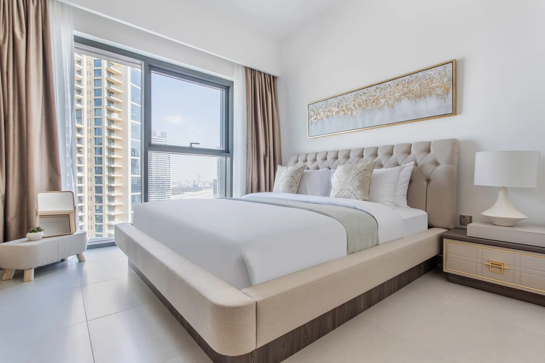 Un dormitorio luminoso con una cama grande junto a ventanas altas.