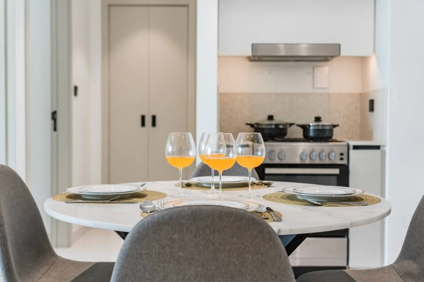 Una mesa de comedor preparada con copas está frente a una estufa de cocina.