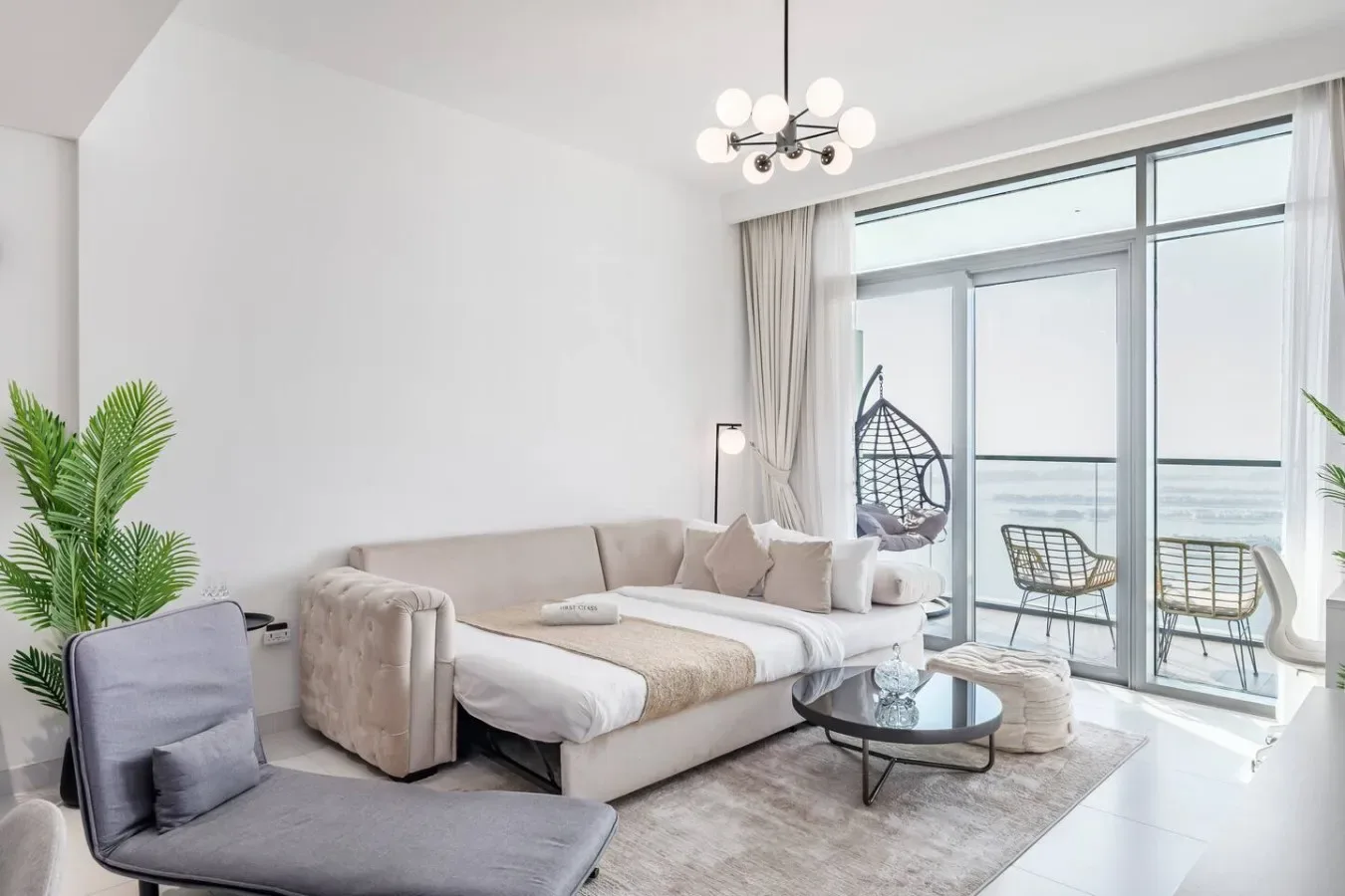 Una sala luminosa con sofá, mesa de centro de vidrio y ventanales grandes.