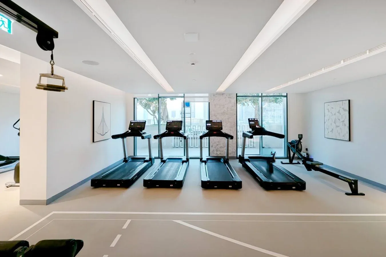 Una luminosa sala de ejercicio con cintas de correr frente a grandes ventanales.