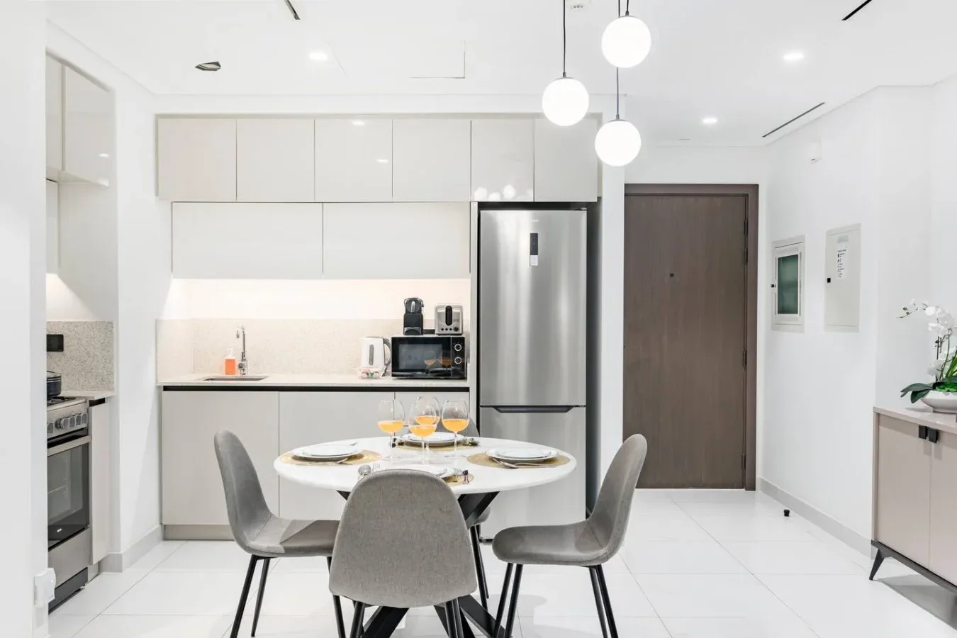 Una cocina y comedor luminosos con una mesa redonda y lámparas colgantes.