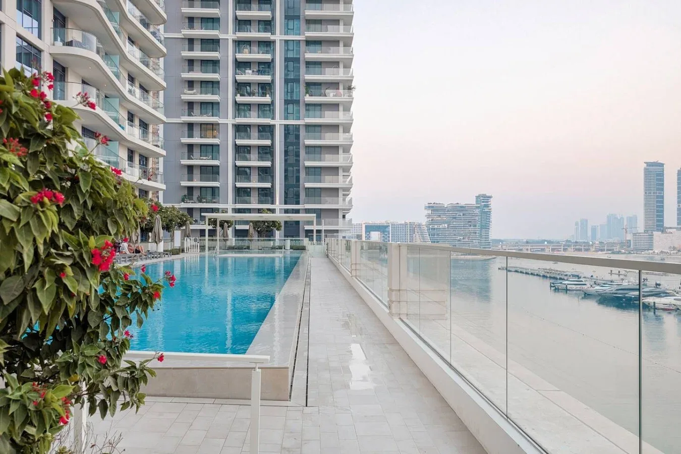 Una piscina en la azotea junto a un edificio alto mira hacia el agua y el horizonte lejano.