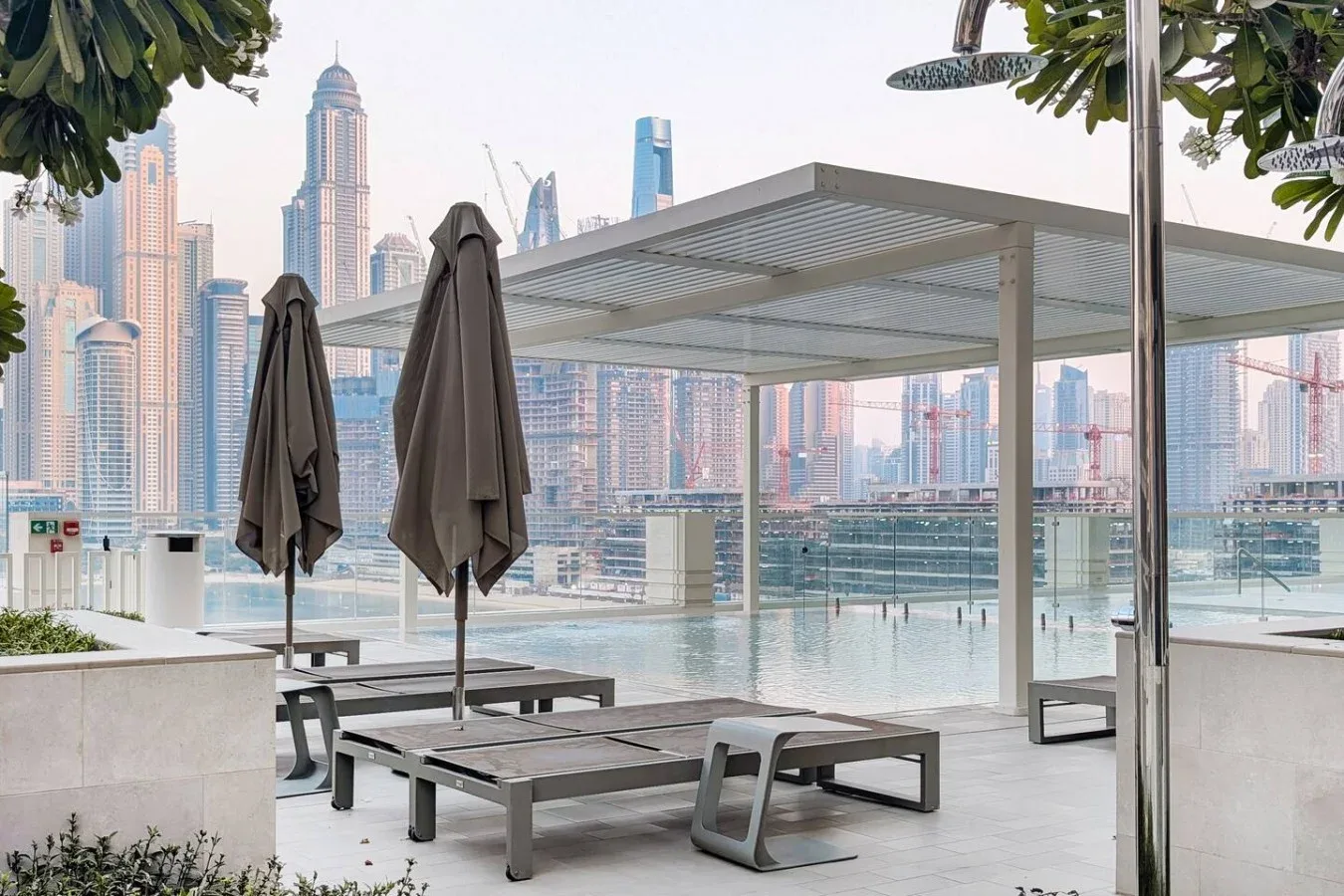 Una terraza junto a una piscina en la azotea, con asientos y edificios al fondo.