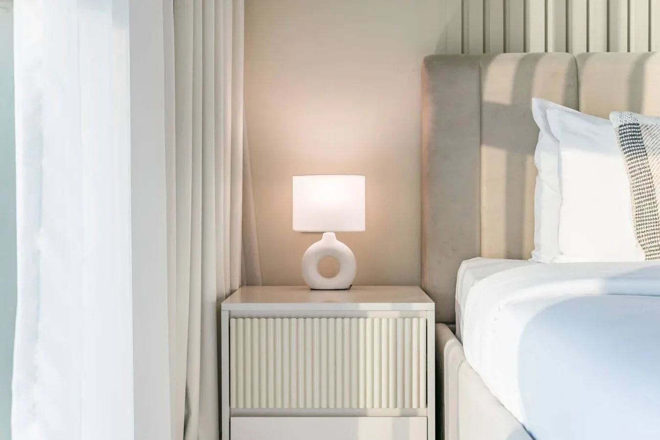 Dormitorio con una mesita de noche y una lámpara encendida junto a la cama.
