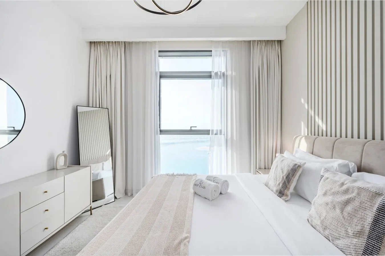 Un dormitorio luminoso con una cama grande, almohadas y una ventana con cortinas.