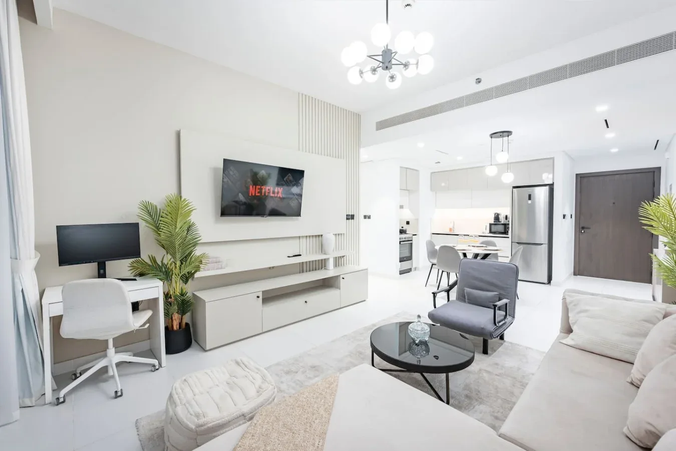 Una sala luminosa con televisor, asientos y una cocina abierta.