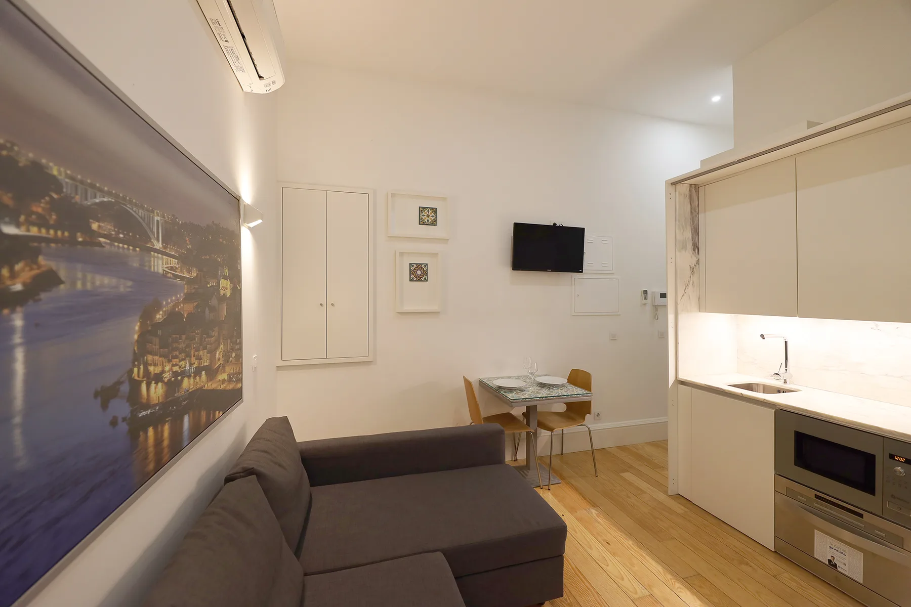 A studio living area with seating, a small dining table, and a kitchenette.