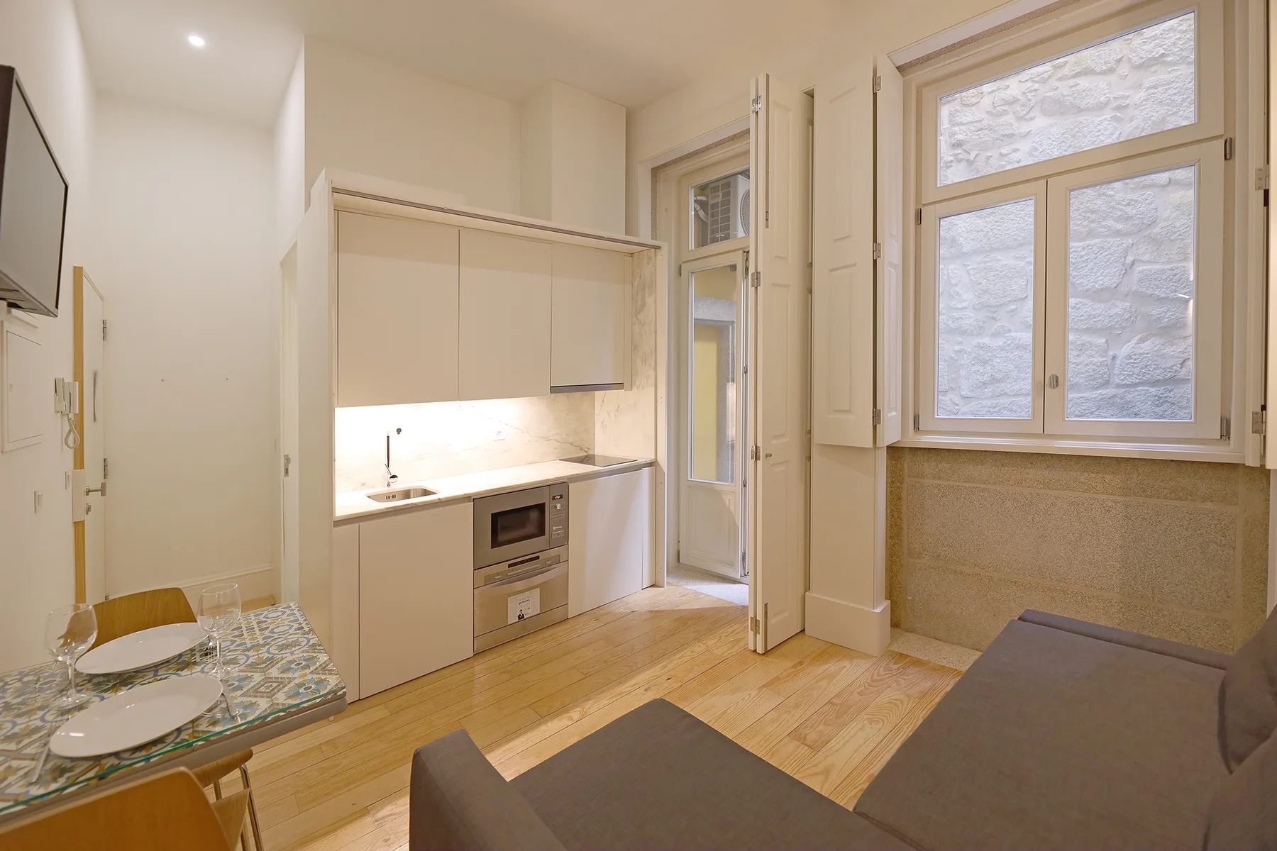 A compact studio interior with a kitchenette, dining table, and seating.