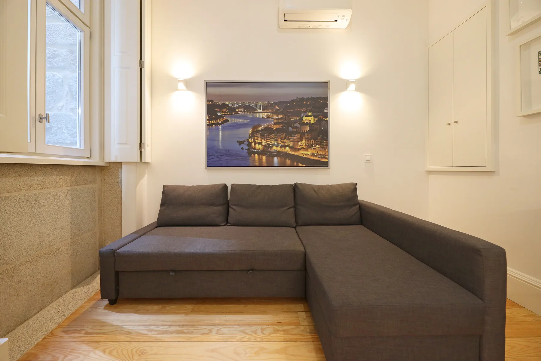 A living area with a dark sectional sofa beneath a framed cityscape.