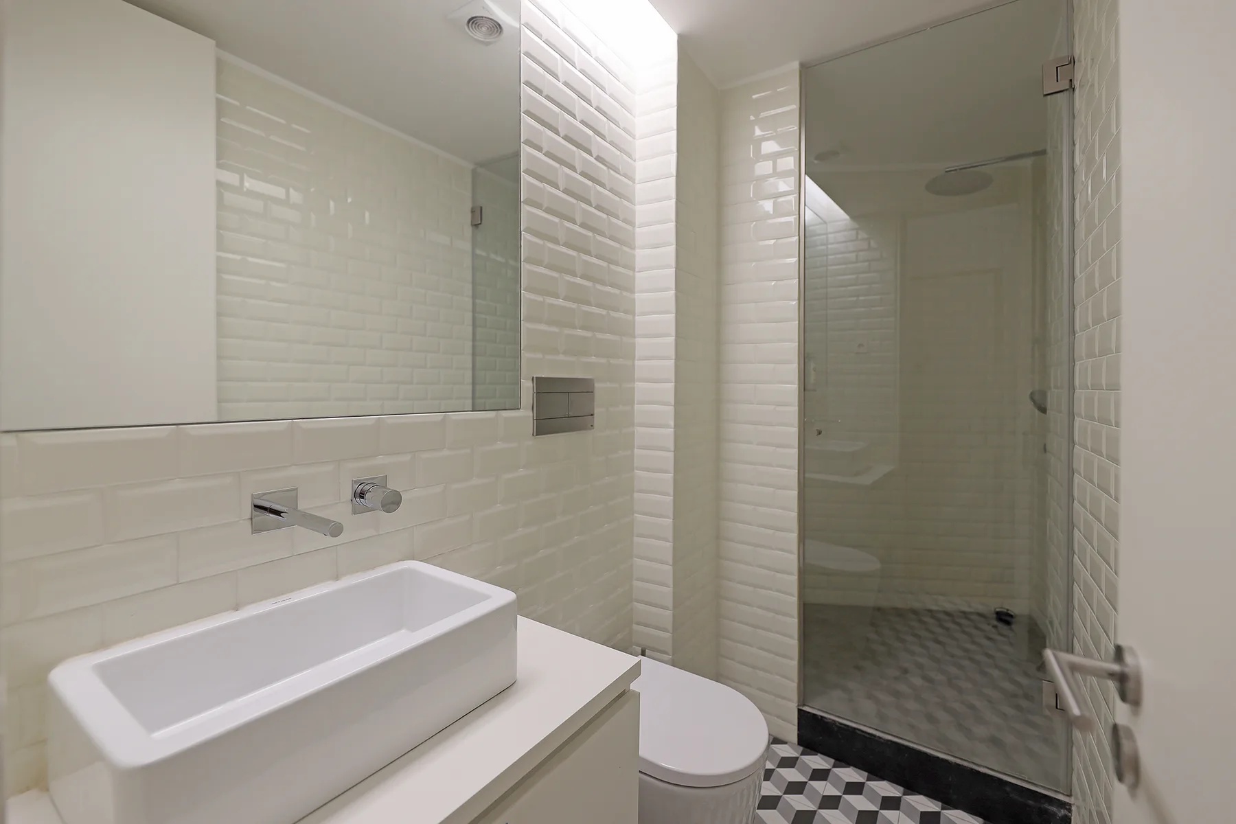 A bathroom with a rectangular sink basin and a glass shower enclosure.