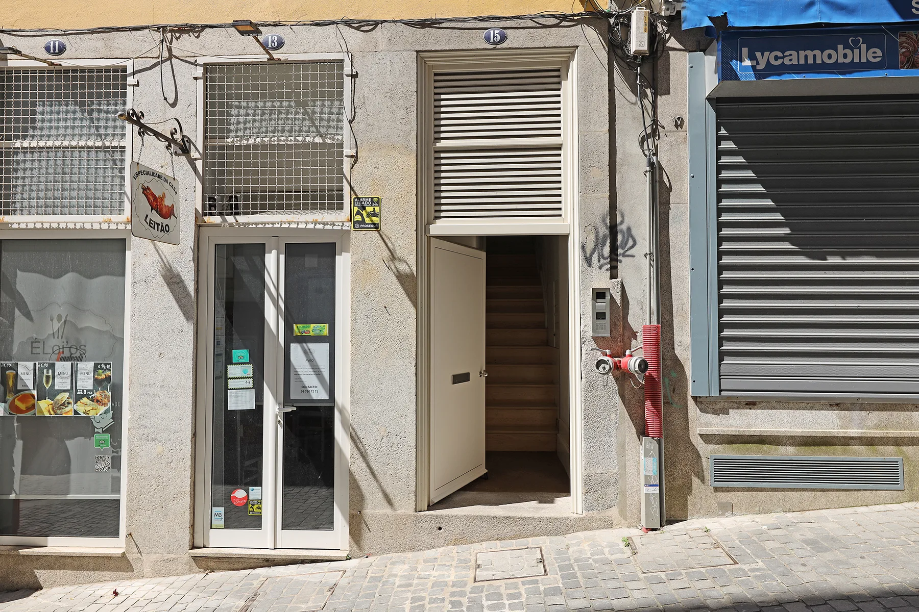A street-facing building entrance sits between storefront windows and a closed metal shutter.