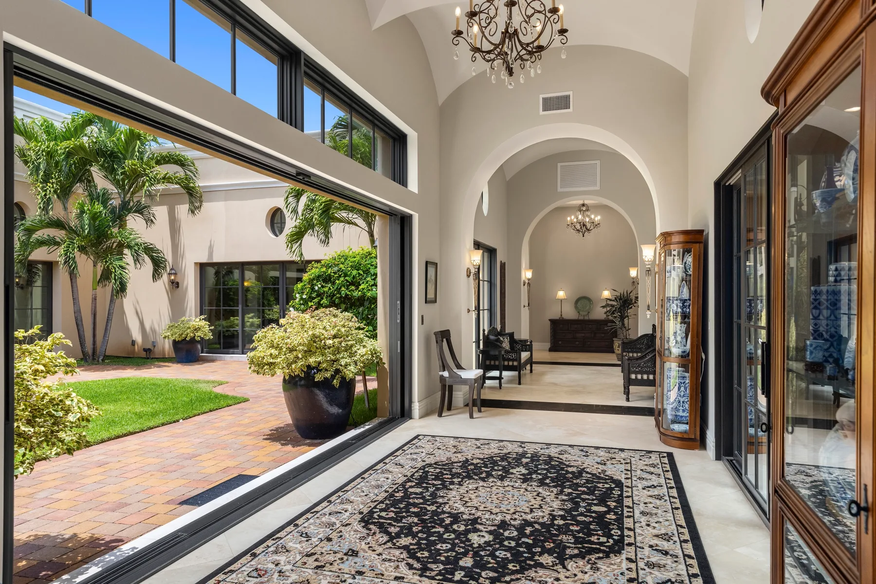 A bright interior hallway opens onto a courtyard, with a patterned rug on the floor.
