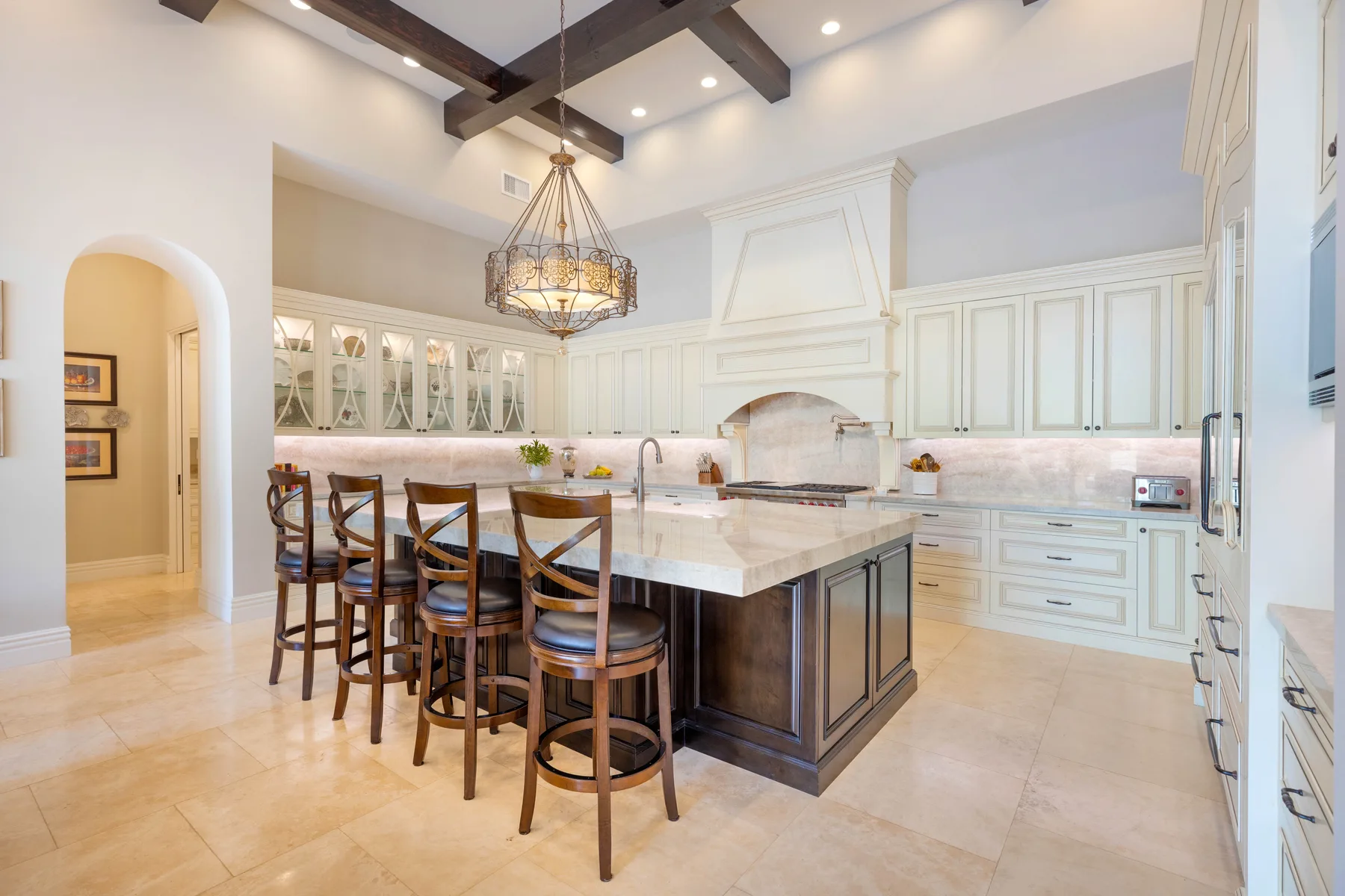 A bright kitchen with a large island and bar seating beneath exposed ceiling beams.