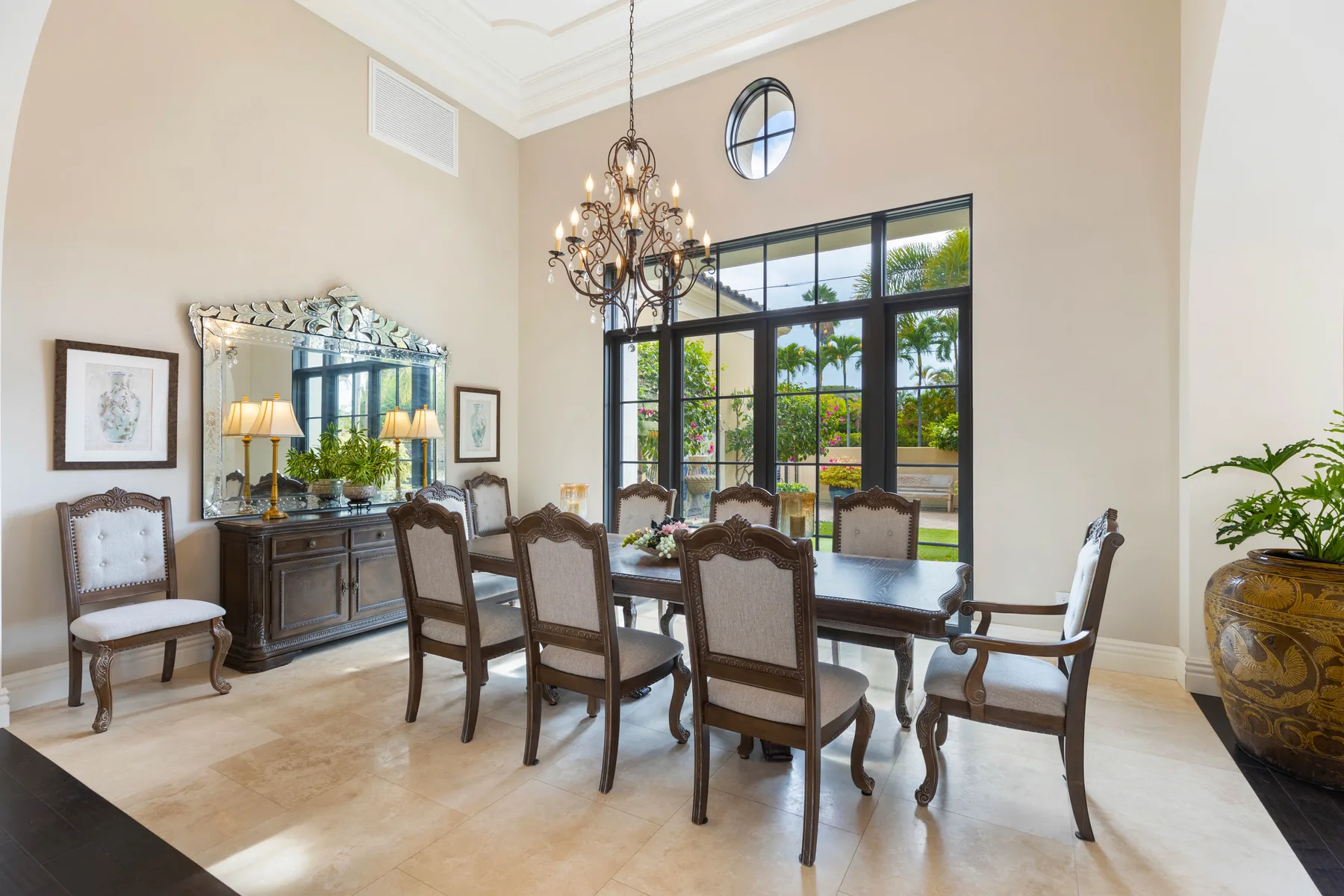 A formal dining room with a long table, upholstered seating, and large windows.