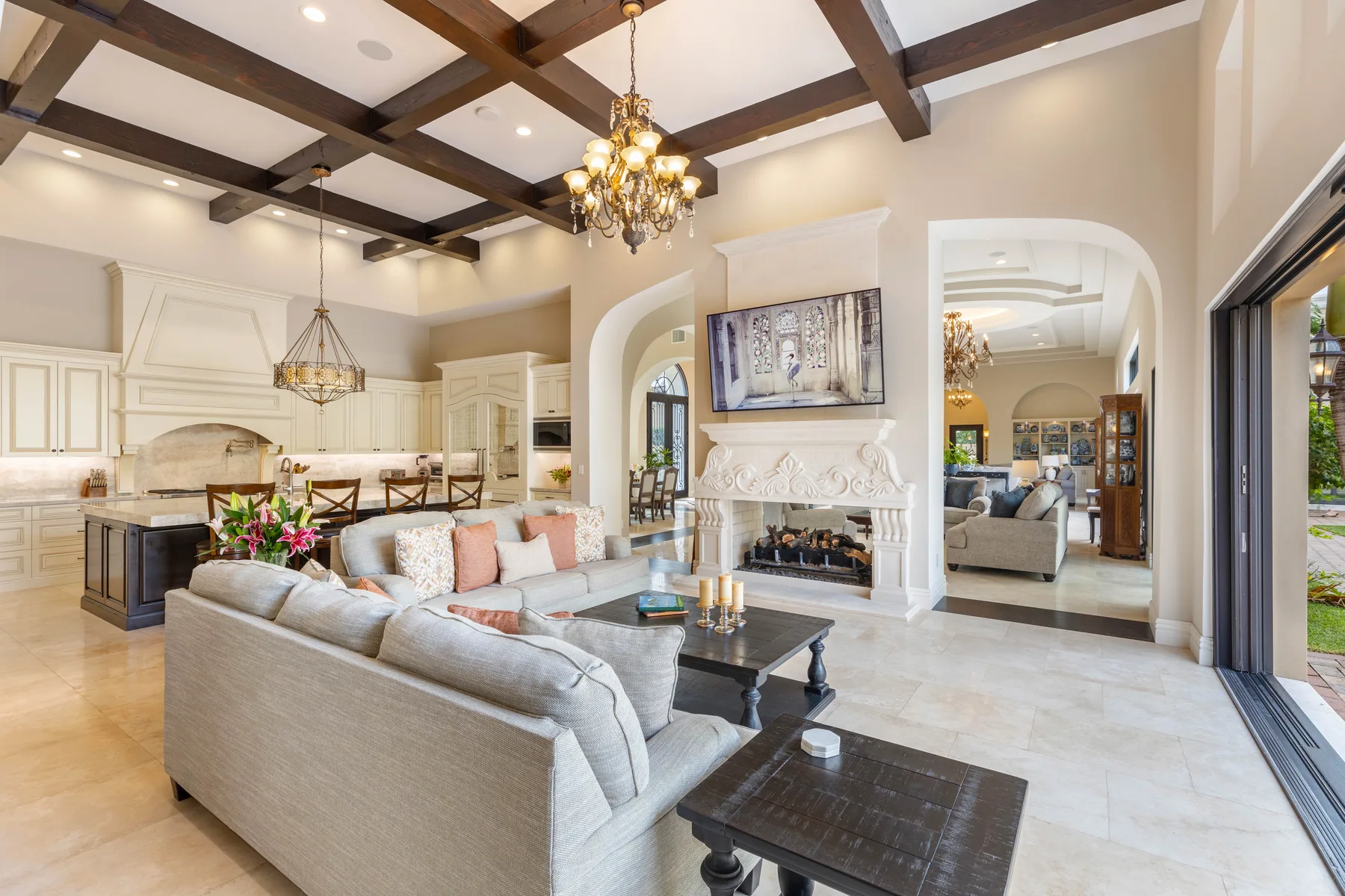 A spacious living room opens into a kitchen, with a fireplace and seating.
