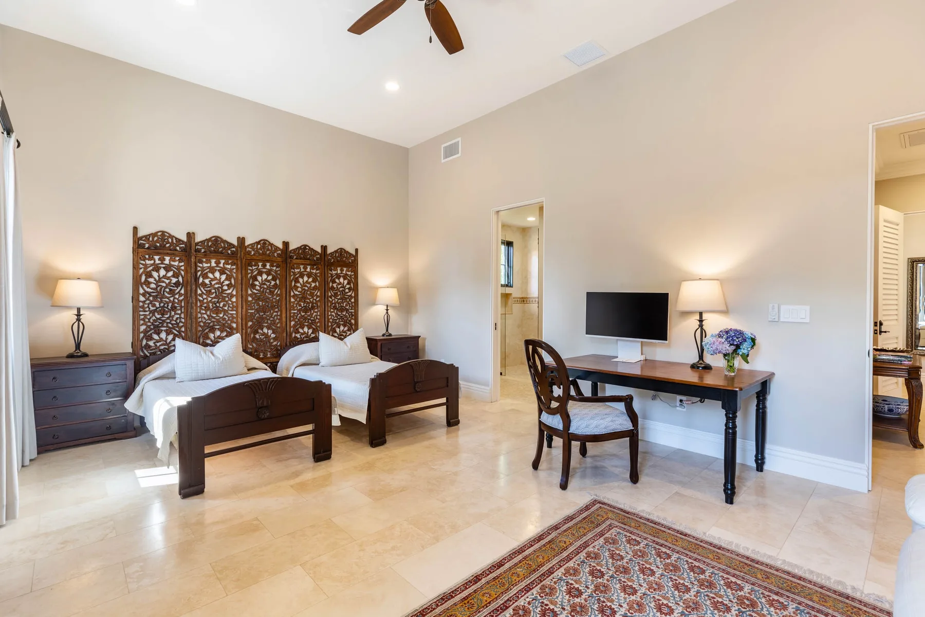 A bedroom with two beds, a desk, and a television.