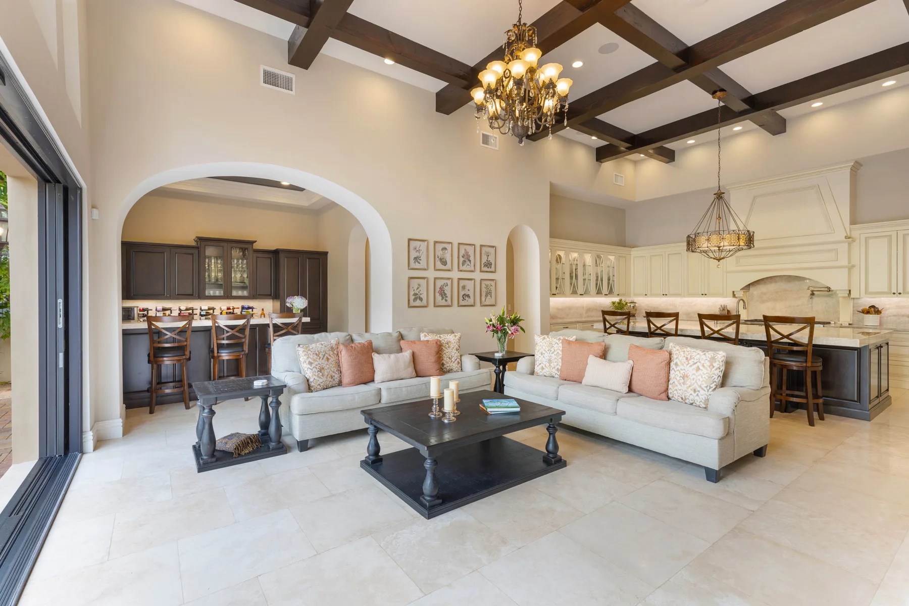 An open-plan living room and kitchen with seating beneath dark ceiling beams.