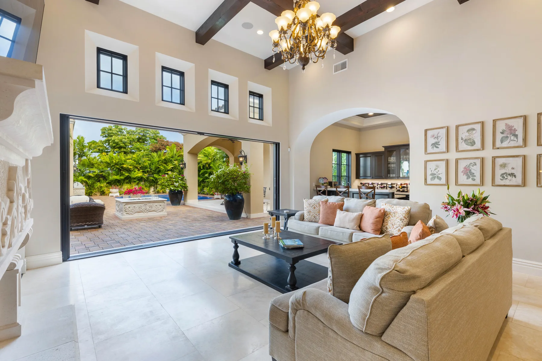 A bright living room opens onto a patio, with seating and a dining area beyond.