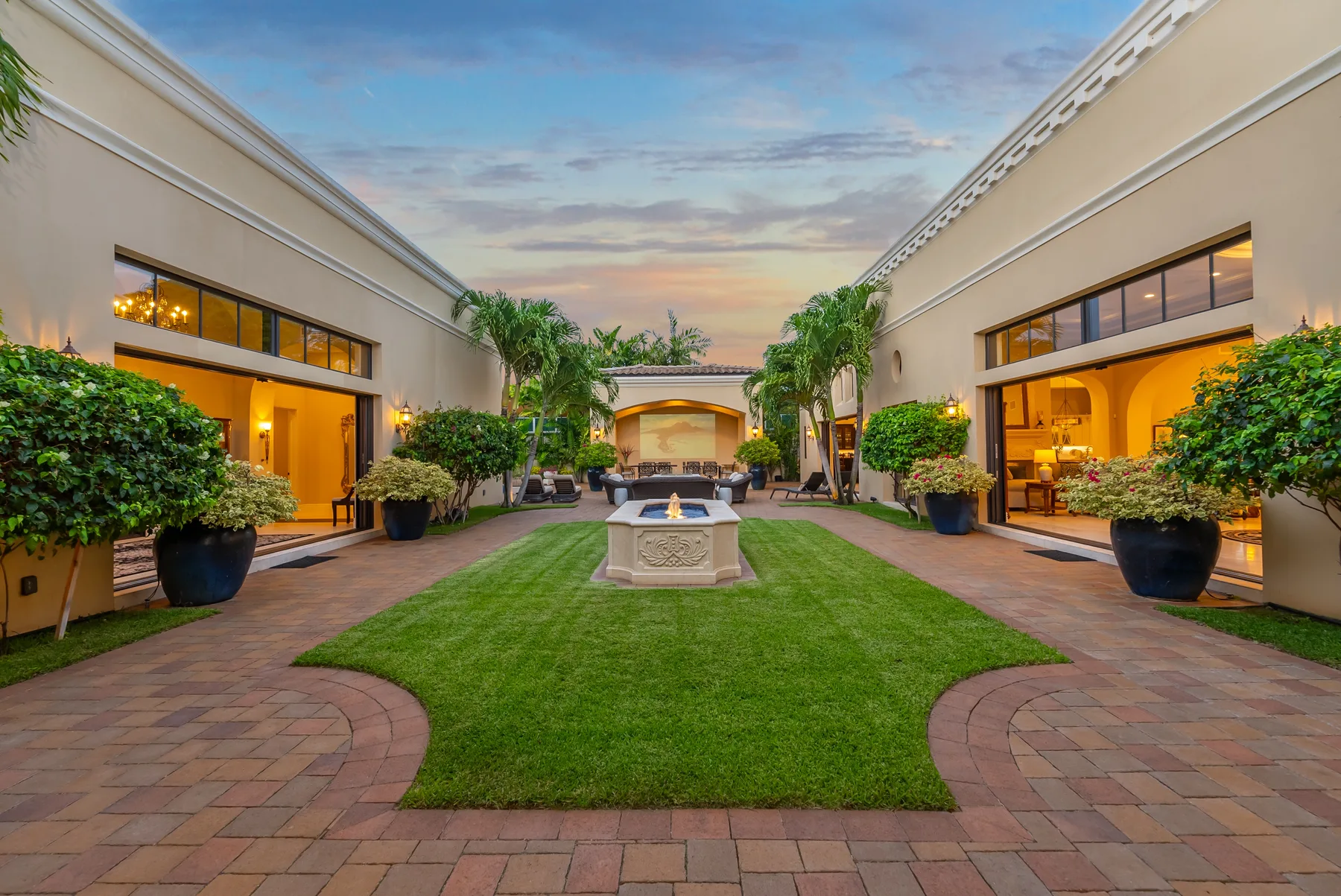 An open courtyard with a central fountain, green lawn, and surrounding walkways.