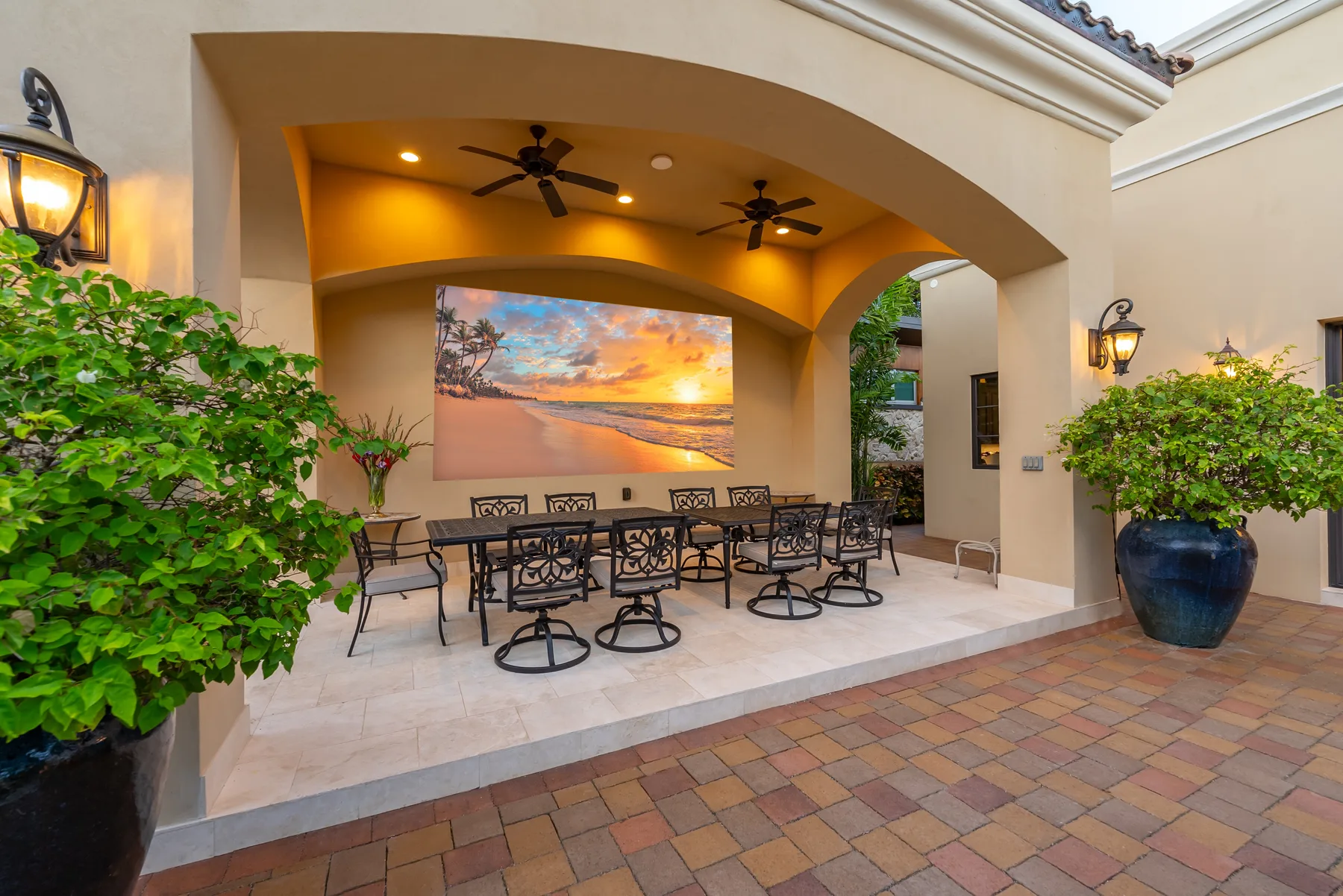 A covered outdoor dining area with tables and chairs beneath an arched ceiling.