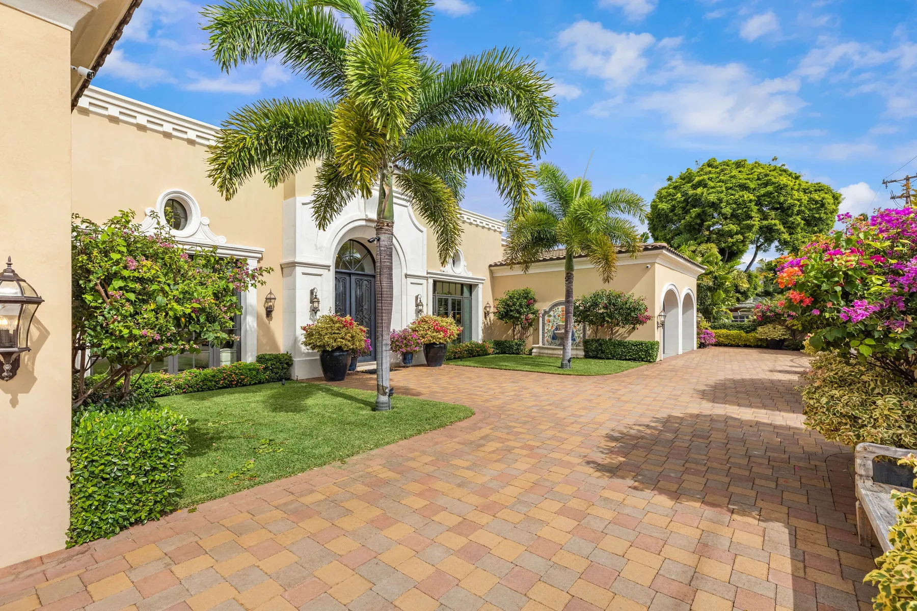 A landscaped courtyard with palm trees, flowering shrubs, and a paved walkway.