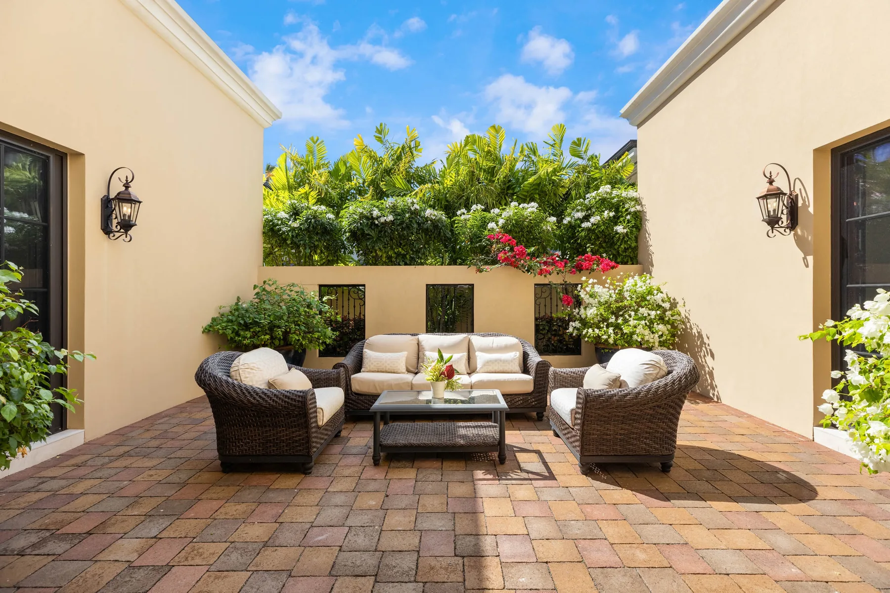 An outdoor seating area between two buildings, with cushioned seating around a low table.