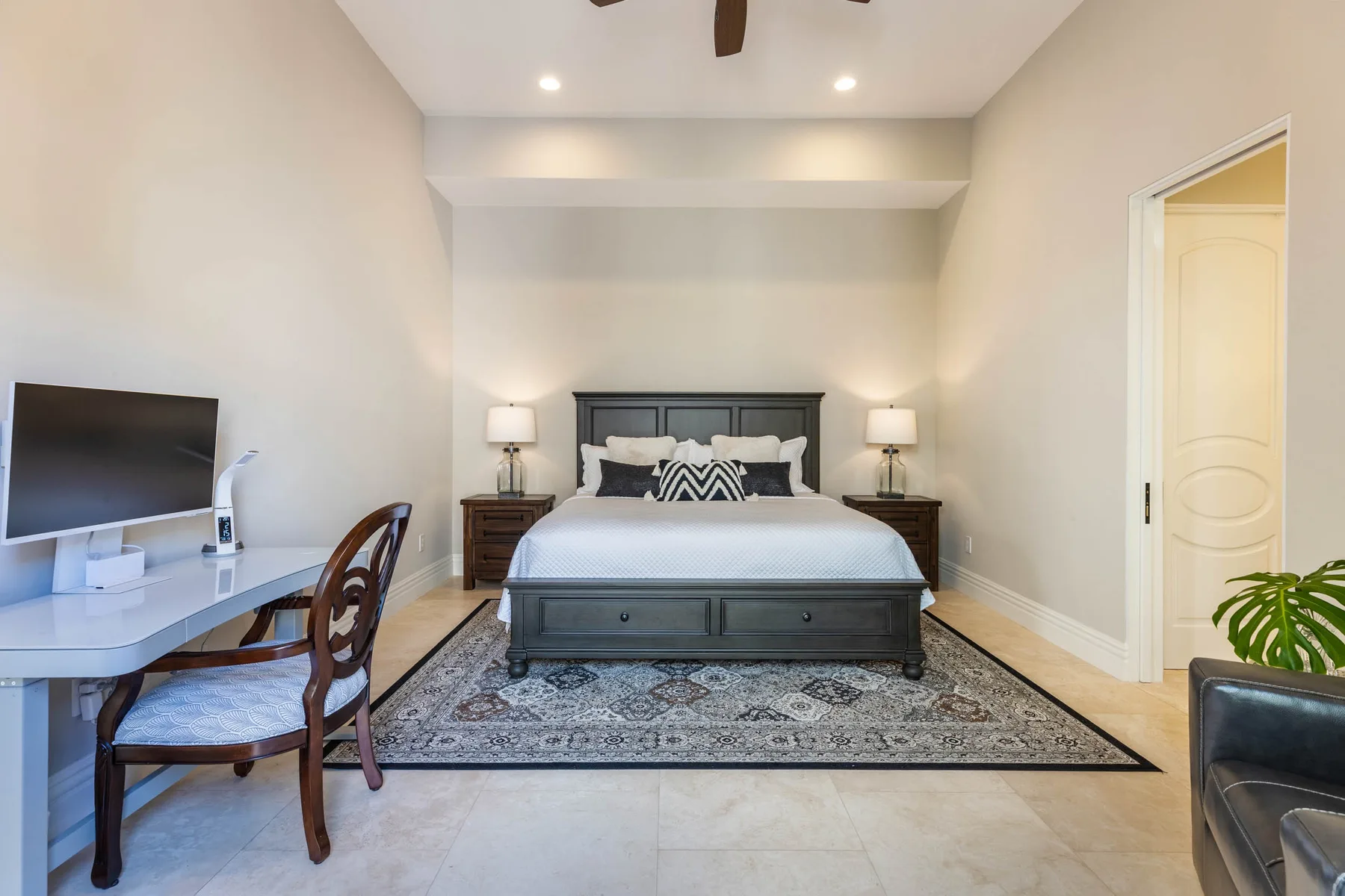 A bedroom with a bed, a desk, and a patterned rug.