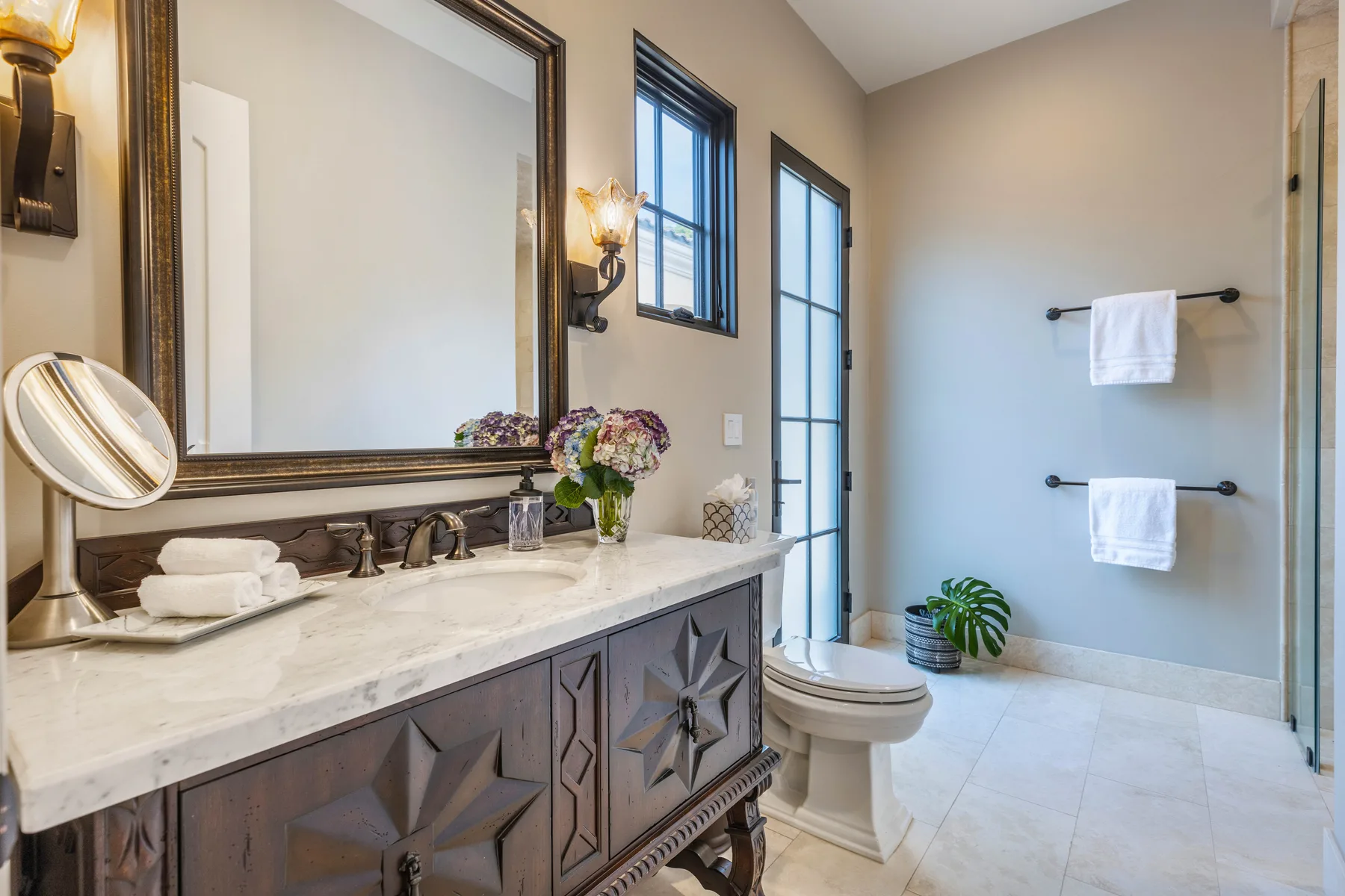 A bathroom with a long vanity, wall mirror, toilet, and towel bars.
