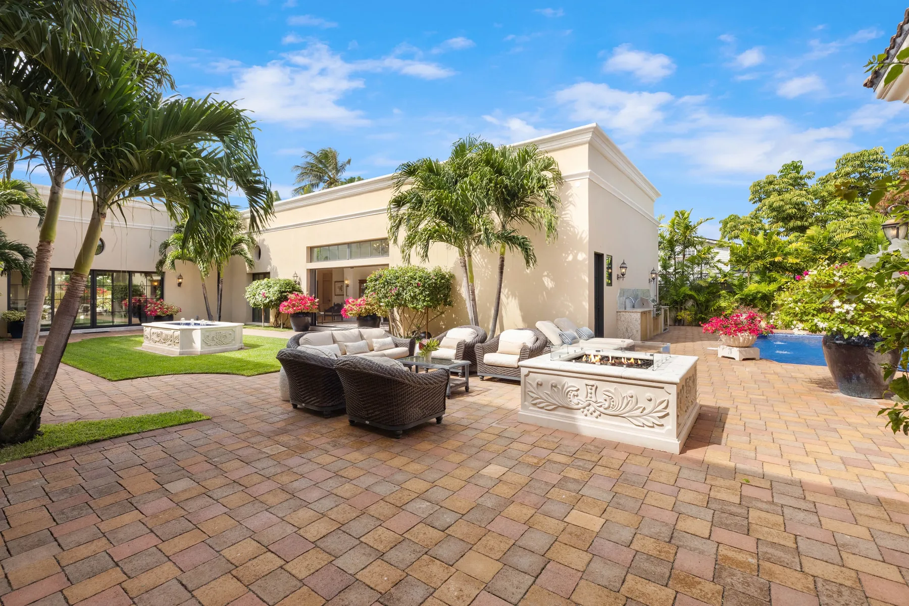 A paved patio with outdoor seating, a decorative water feature, and a swimming pool.
