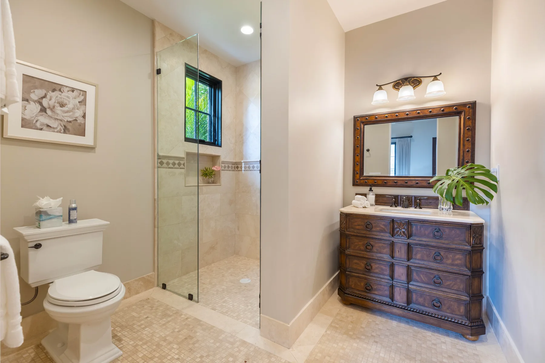 A bathroom with a glass shower and a wooden vanity beneath a large mirror.