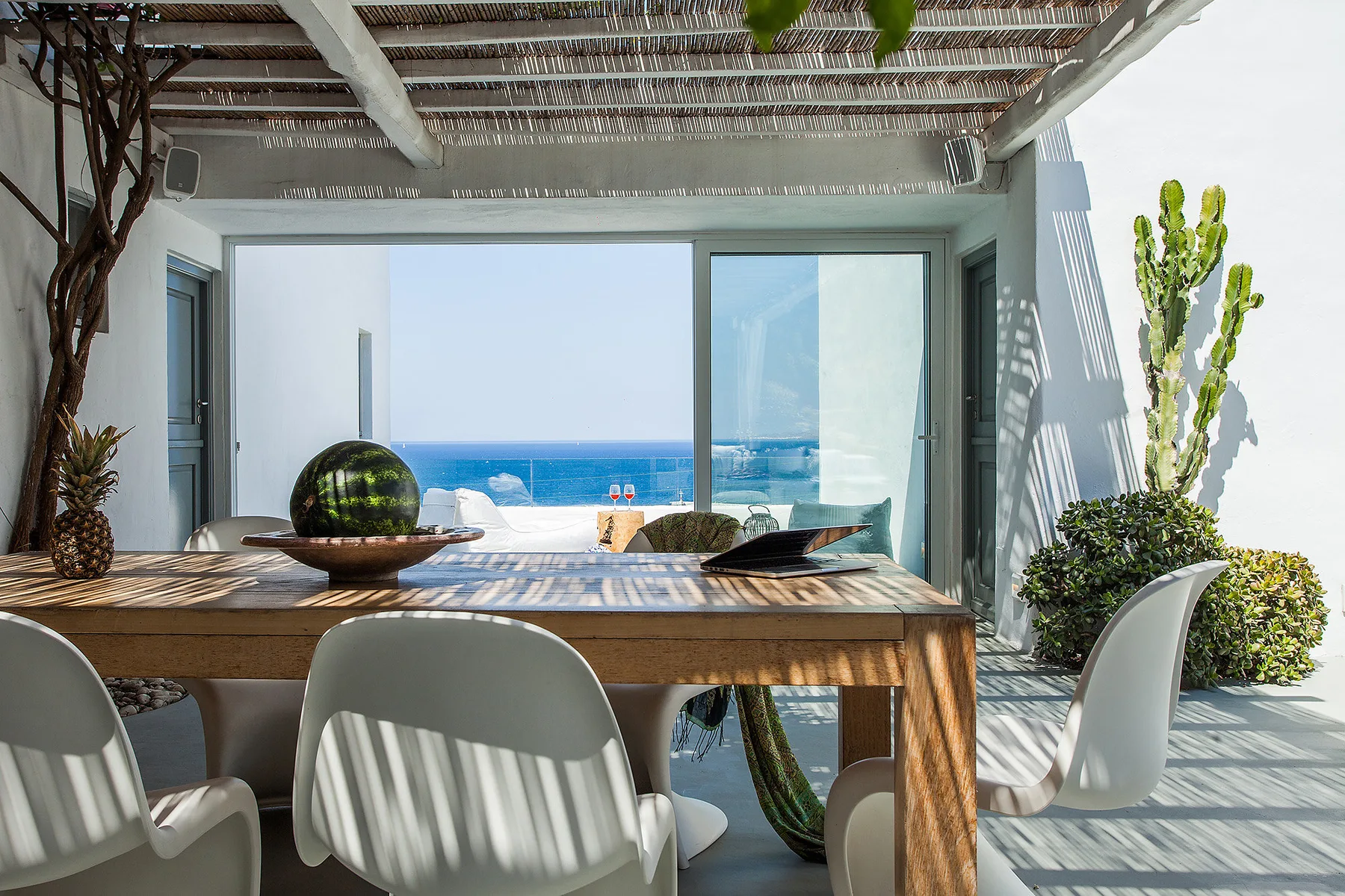 Una zona de comedor exterior cubierta se abre a una vista del mar.