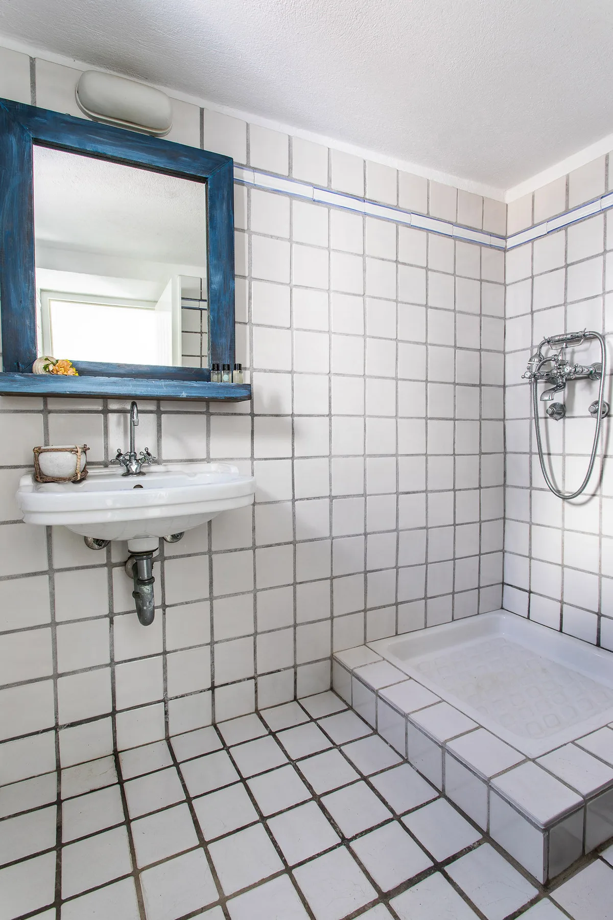 Un baño de azulejos con lavabo, espejo y ducha.