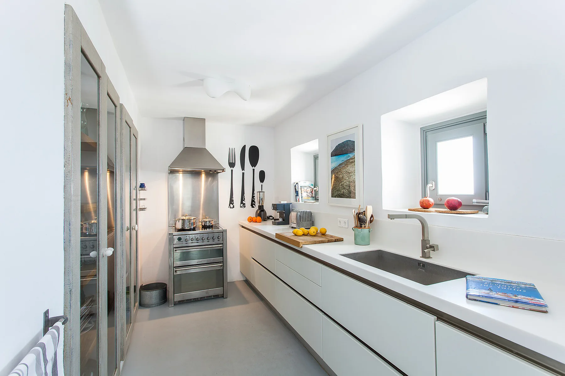 A bright modern kitchen with a long counter and cooking range.