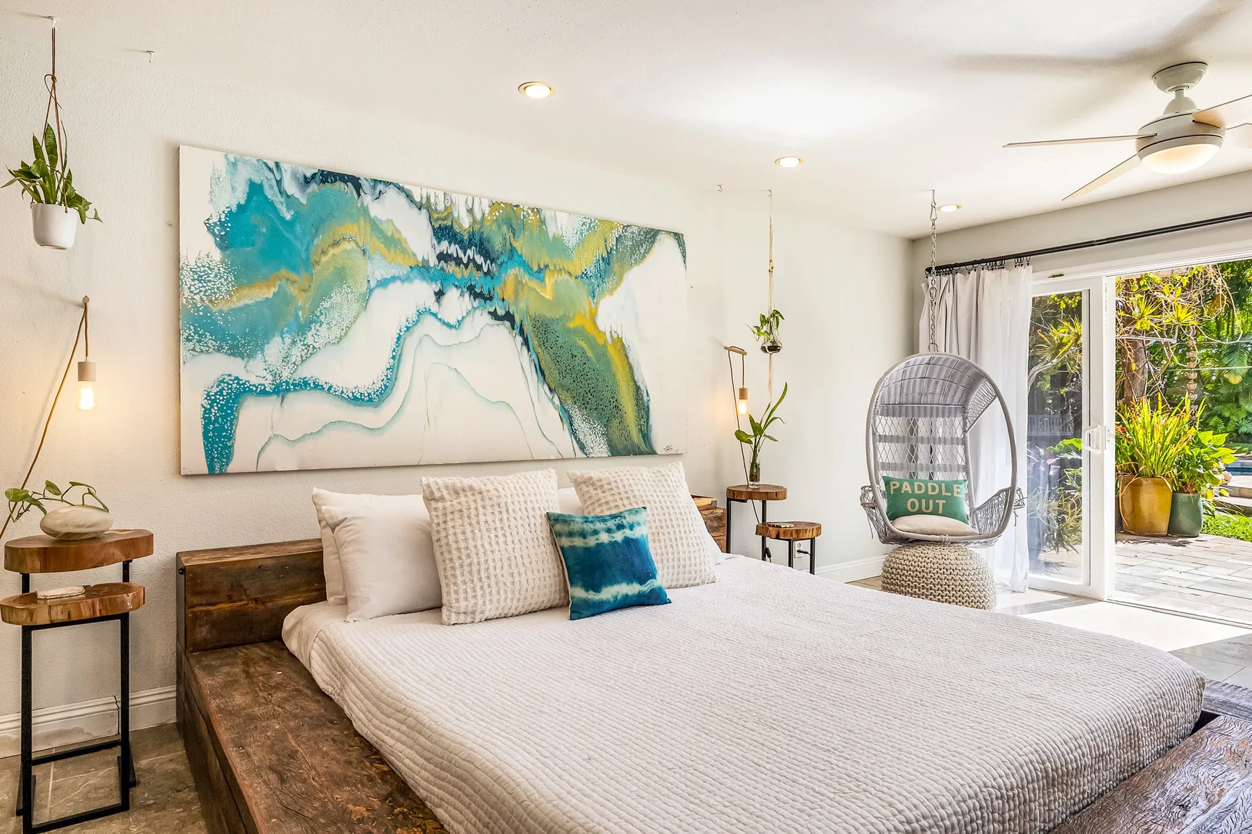 Un dormitorio con una cama, arte colorido en la pared y puertas corredizas de vidrio que dan a un patio.