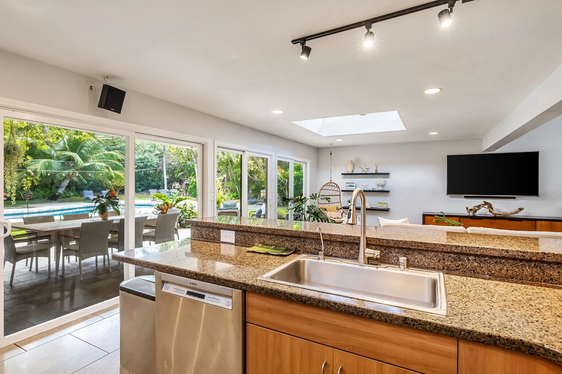 Una cocina luminosa con una amplia encimera y ventanas con vistas a un jardín.