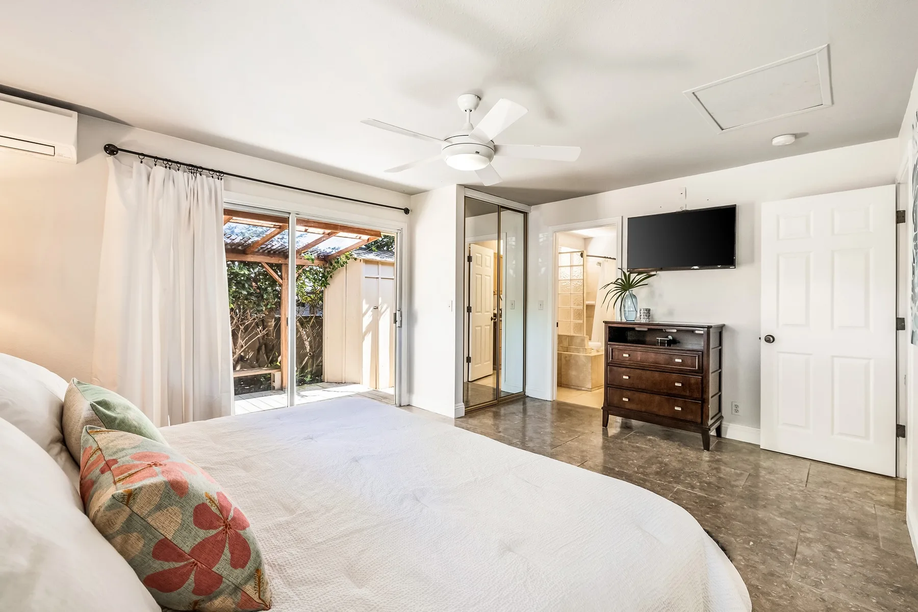 Un dormitorio con una cama, puertas corredizas de vidrio y un televisor.