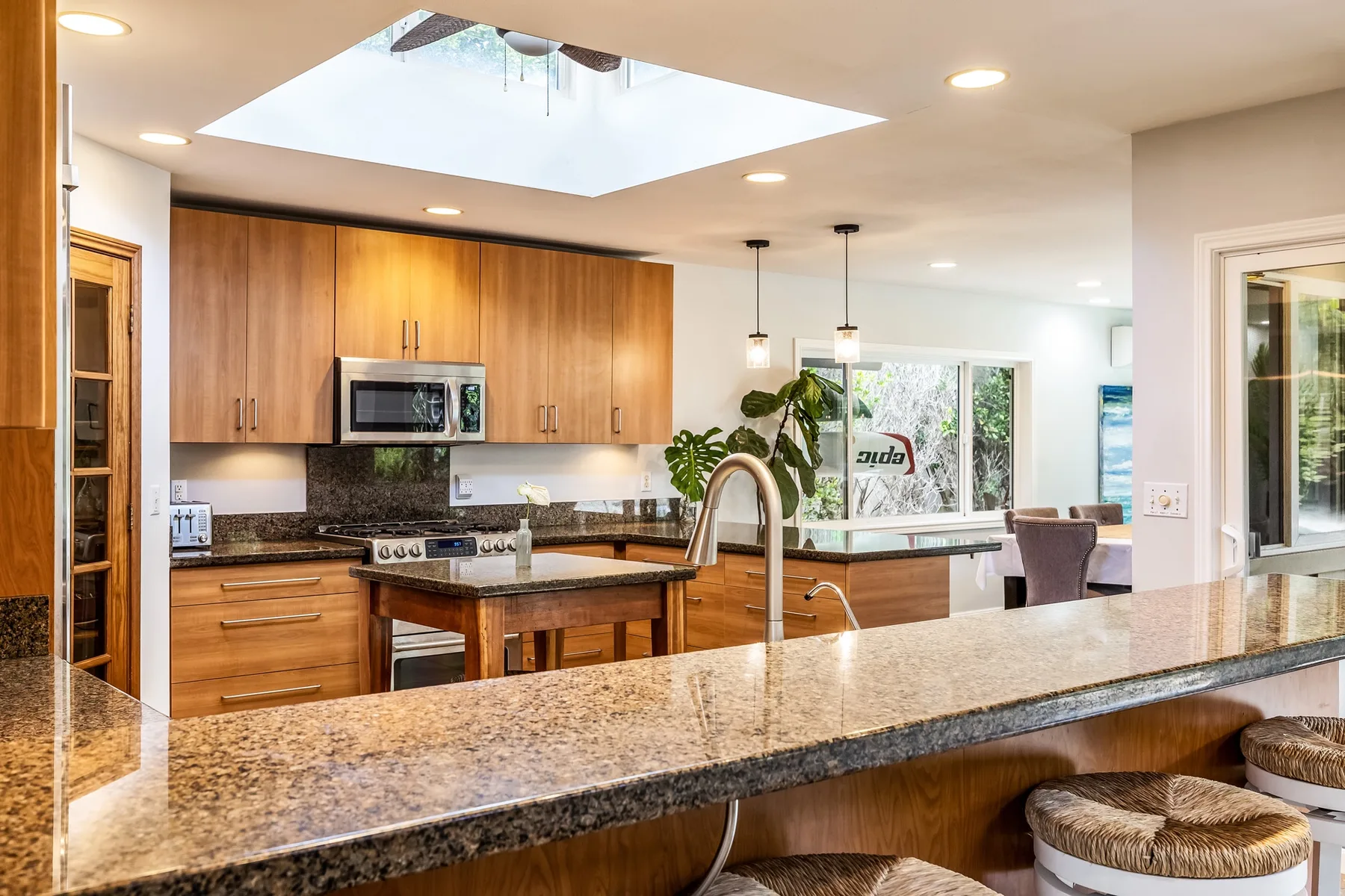 Una cocina luminosa con gabinetes de madera, una isla central y una encimera de granito.
