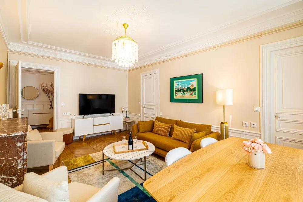 A living room with seating around a coffee table and a television.