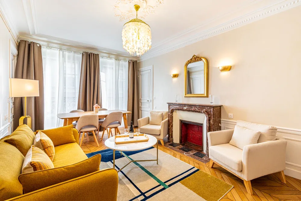 A bright living room with seating arranged around a coffee table and fireplace.