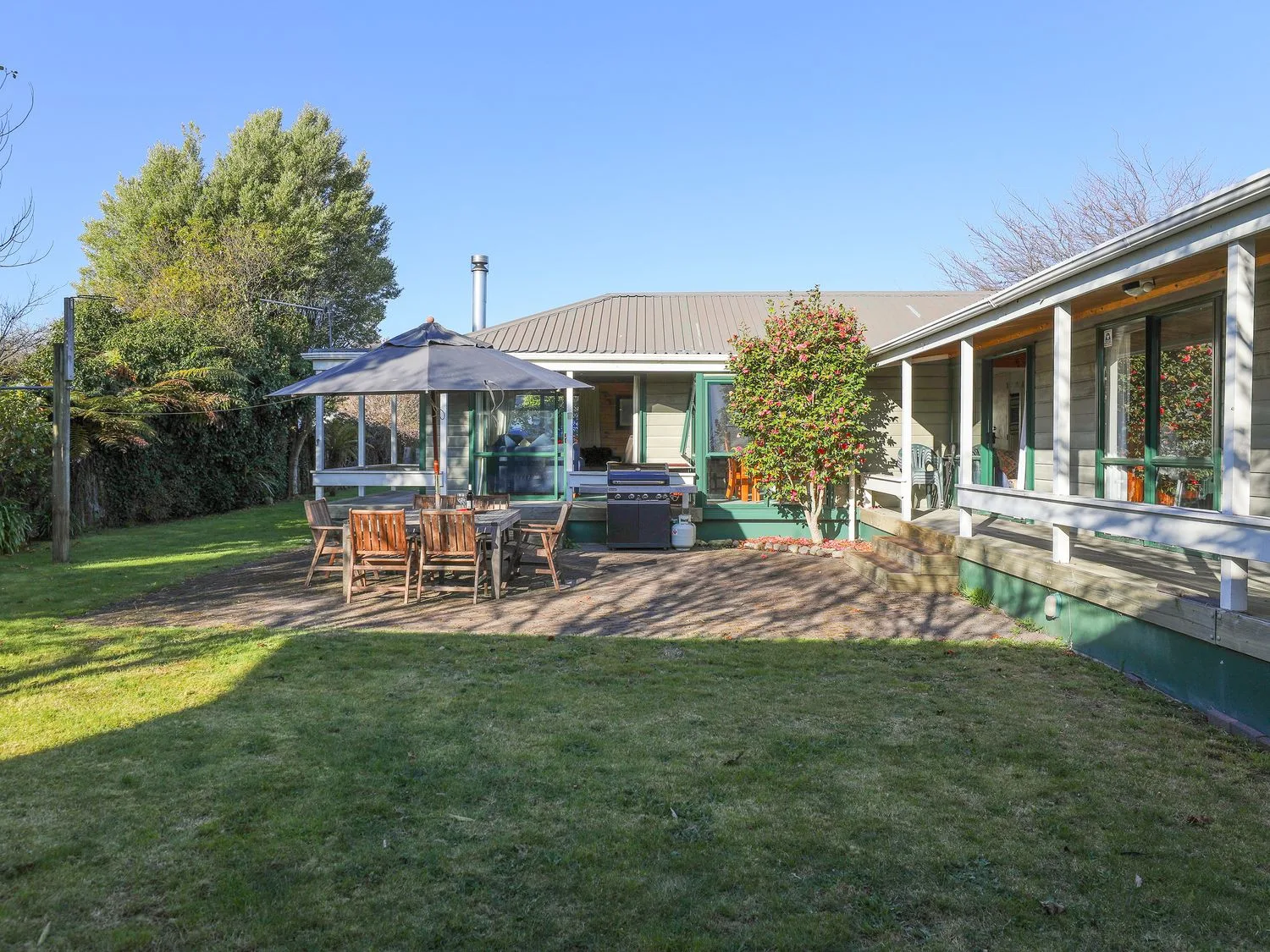 Un patio trasero con asientos al aire libre y una parrilla junto a una casa de una planta.