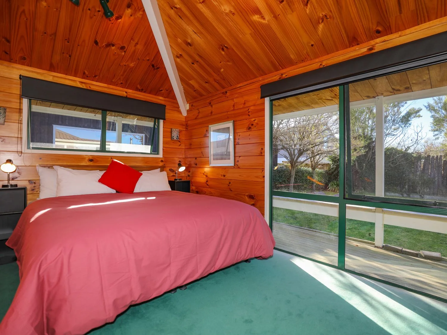 Un dormitorio con una cama cubierta con ropa de cama rosa junto a puertas corredizas de vidrio.