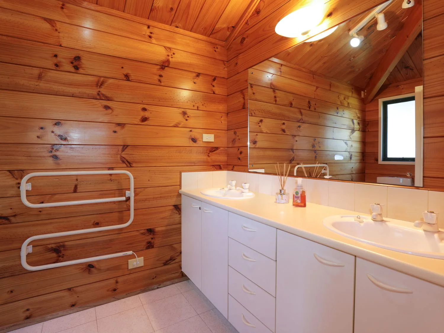Un baño con un tocador largo, dos lavabos y paredes revestidas de madera.